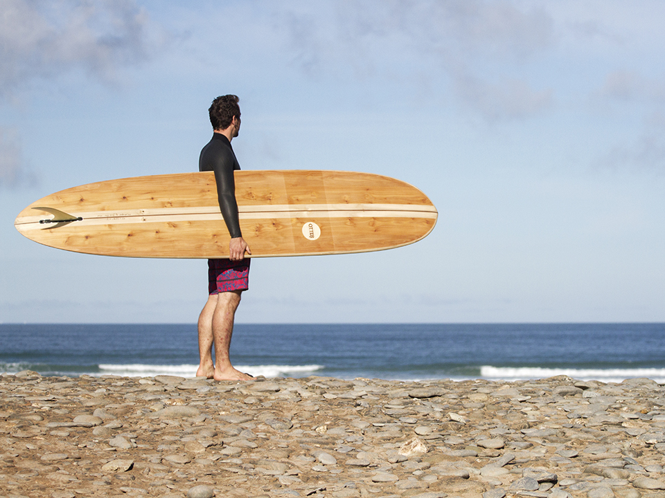 James Otter on the beach at Godrevy beach with wooden longboard, Otter surfboards wicket.