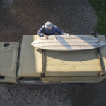 James Otter with a Wooden surfboard on top of a Landrover Defender. Clipper