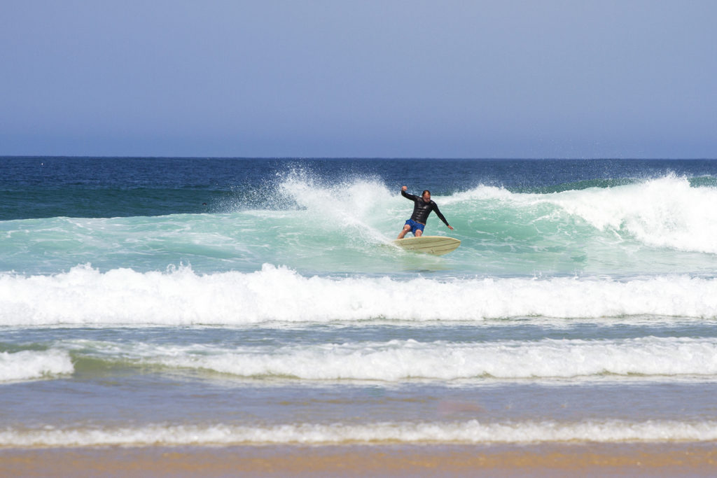 Dan Crockett leans into a turn at Gwithian in the summer in Cornwall on his Clipper Otter Wooden surfboard.