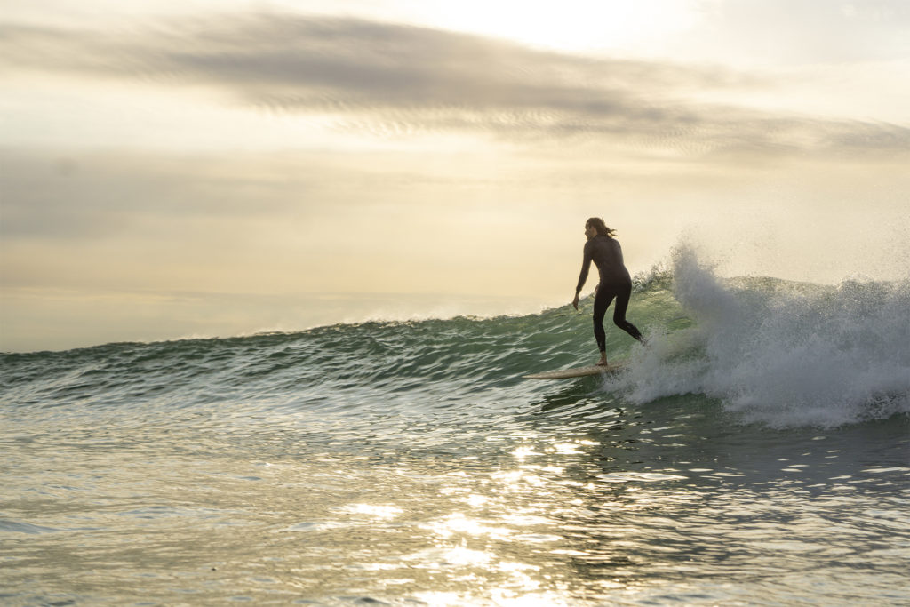 Lawrence Stafford high lining in the sun on an Otter Wooden Coaster Surfboard at Gwithian in Cornwall