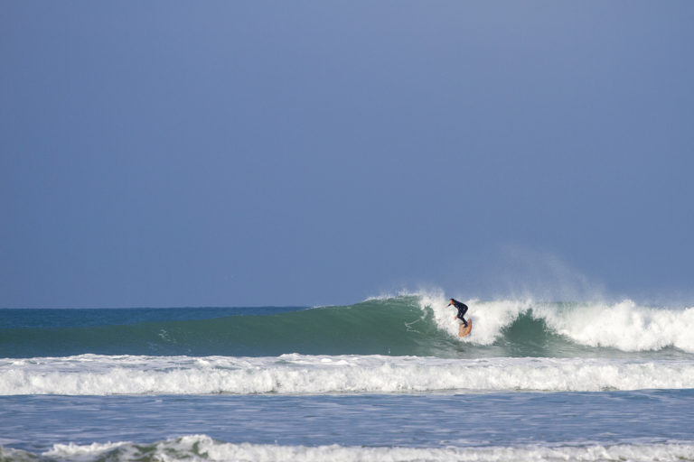 Sarah taking off on the otter surfboards wood burner Wooden surfboard at Gwithian, Cornwall shot from the beach