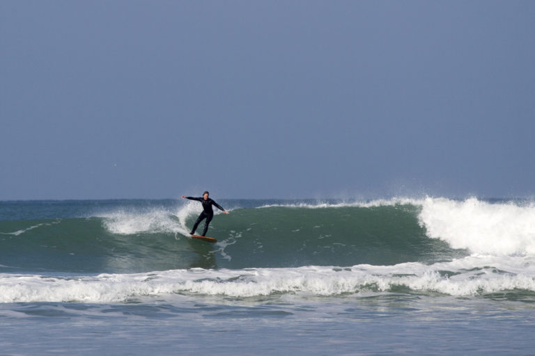 Sarah wrap around on the otter surfboards wood burner Wooden surfboard at Gwithian, Cornwall shot from the beach
