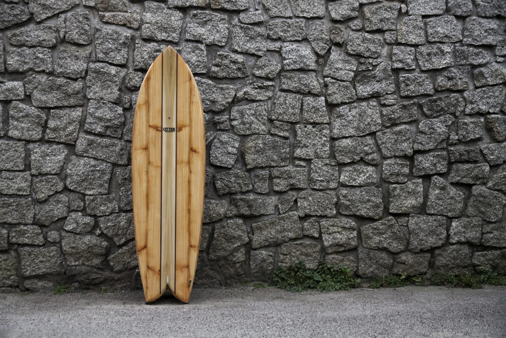 biff lancaster wooden otter surfboard woodburner fish against a stone wall