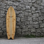 biff lancaster wooden otter surfboard woodburner fish against a stone wall