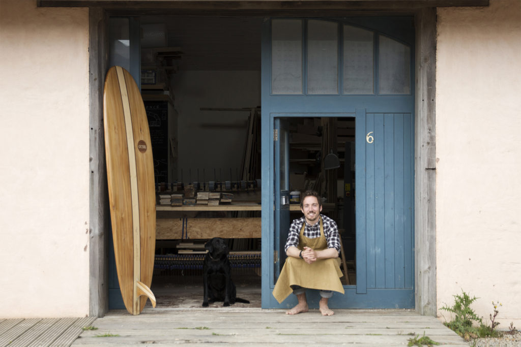 James Otter Wooden surfboard maker in his workshop in Cornwall with his dog, buddy