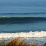 Chris and Gideon paddle over a wave with Otter Surfboards wooden Island Hopper and Jetty at Gwithian