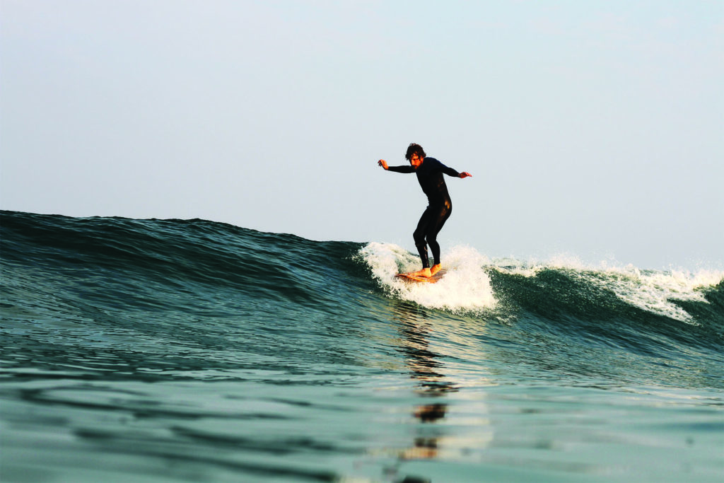 Chris Brunt cross stepping on a Seasaw Wooden Otter Surfboard in surf