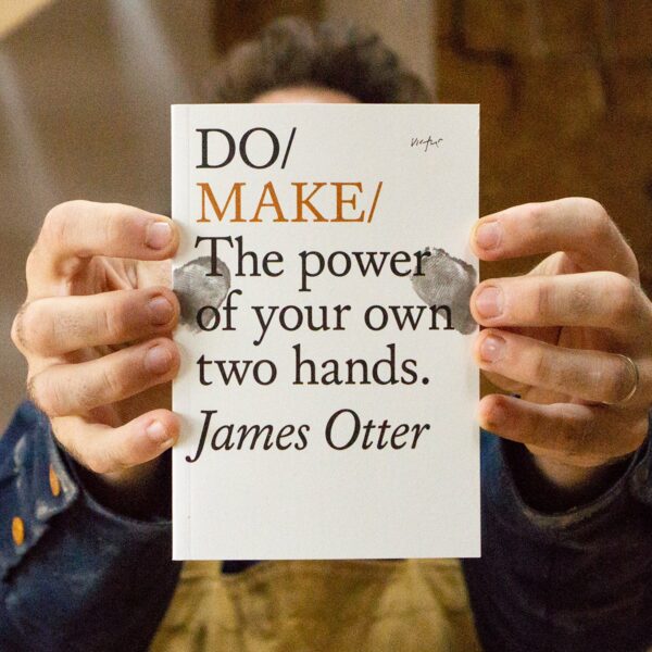 James Otter holding his book Do Make in the Otter Surfboards Workshop
