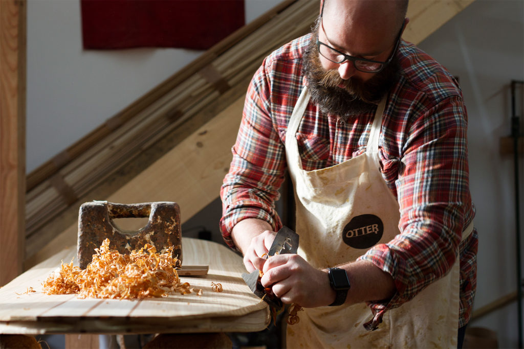 Stuart planing the rails of his wooden surfboard in the otter workshop cornwall