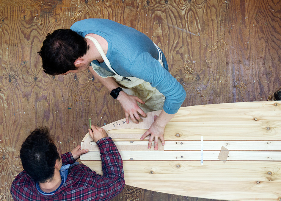 James Otter and Greg look at wooden surfboard template