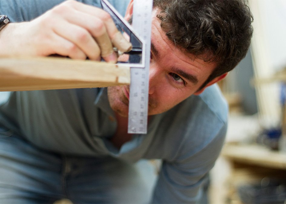 Greg Checking the rails with a square on his wooden surfboard in the otter workshop