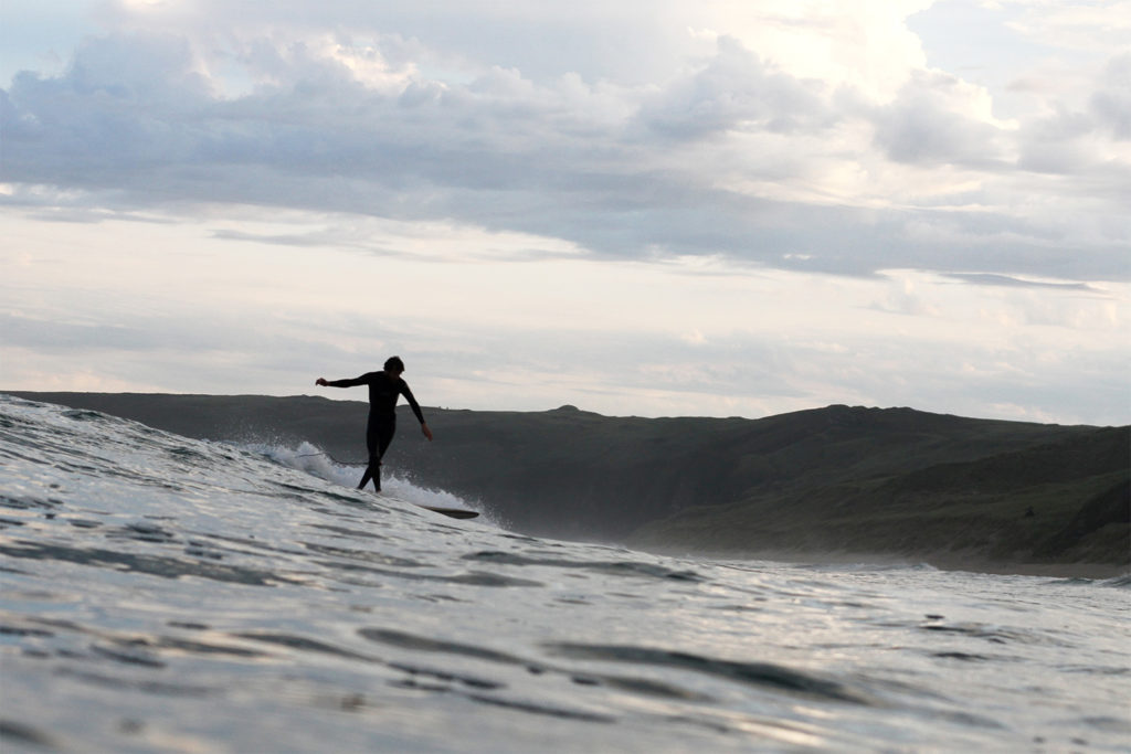 Chris Brunt Cross-steps on a wooden longboard surfboard