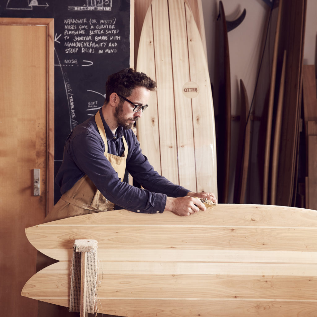 James Otter shaping wooden surfboard fish