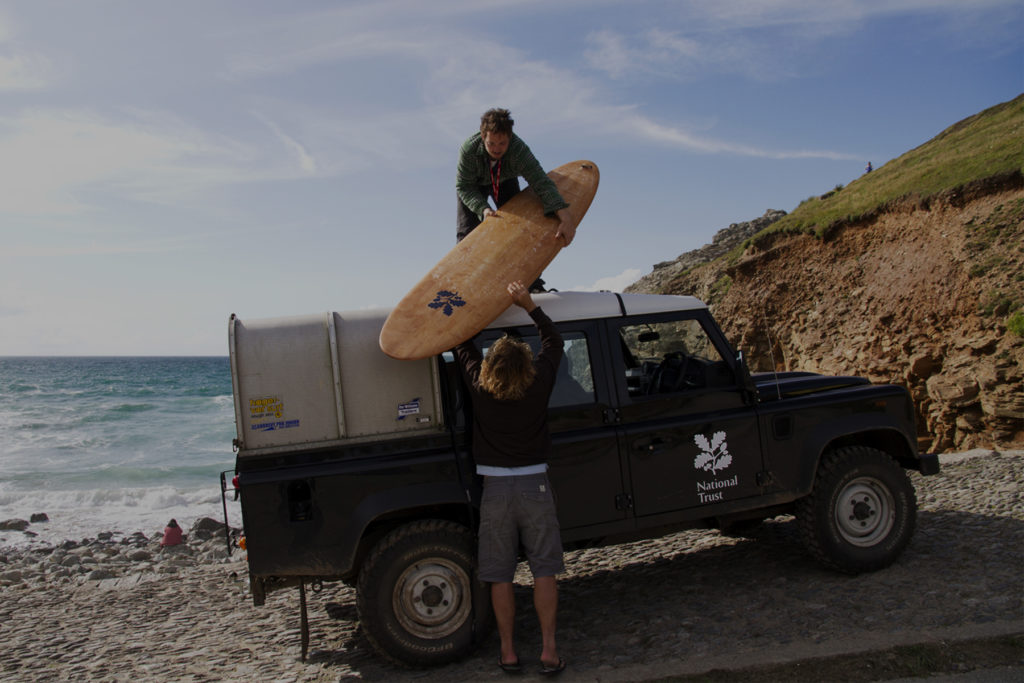 national trust wooden surfboard handover with grey overlay