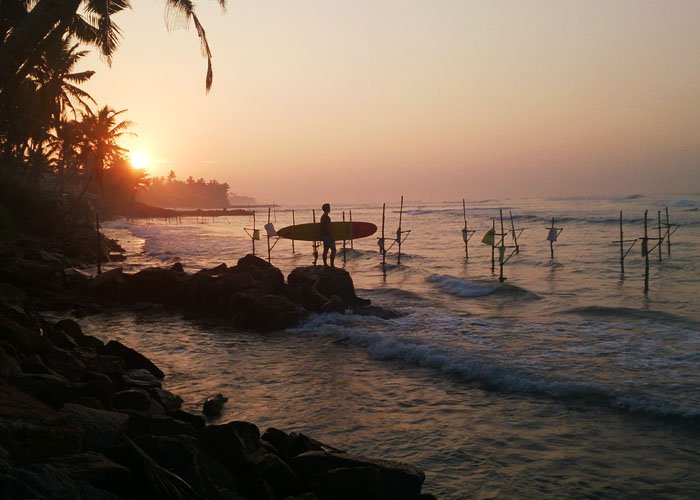 sri lanka surfer at dawn with iconic fisherman perches