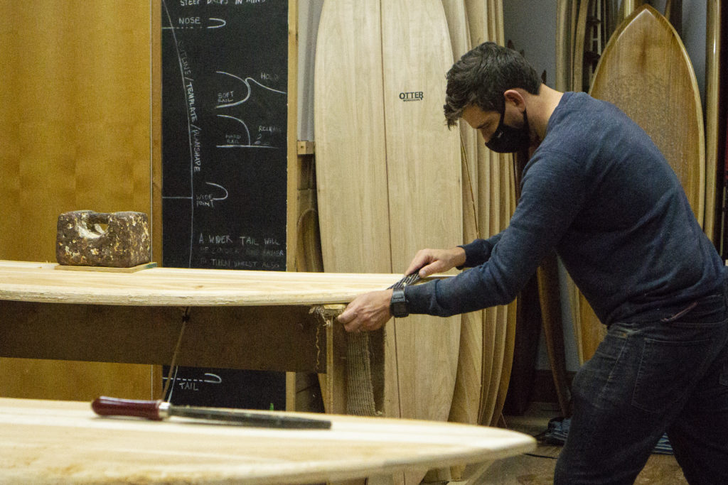 Harry, Chris and James Otter with wooden surfboards at the otter surfboards workshop in cornwall chris shaping tail