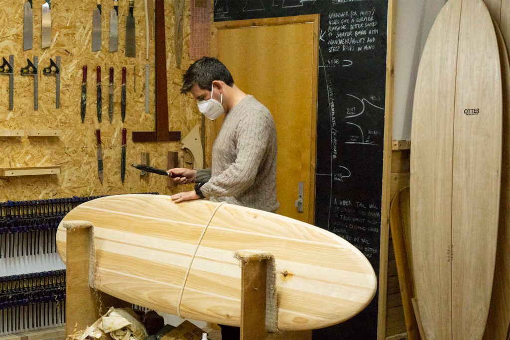 Harry, Chris and James Otter with wooden surfboards at the otter surfboards workshop in cornwall chris rasping rails