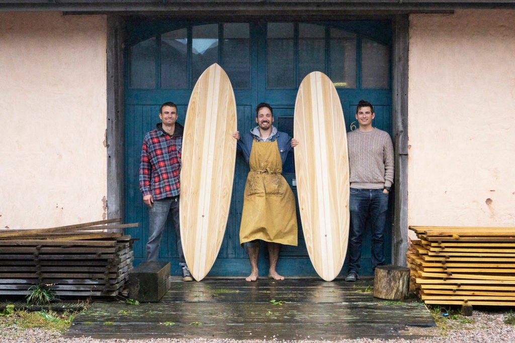 Harry, Chris and James Otter with wooden surfboards at the otter surfboards workshop in cornwall