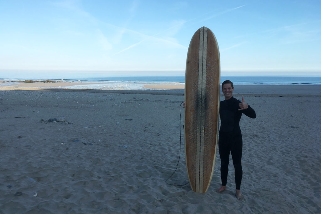 Otter Surfboards Wooden Surfboard Workshop Course Porthtowan Cornwall Guillaume on the beach with wooden longboard
