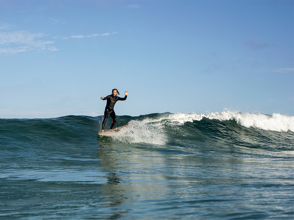 Otter Surfboards wooden surfboard making course with Ben and Marlow Ben surfing past on a longboard