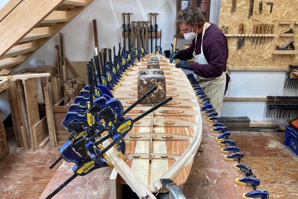 Sam gluing rail strips wooden surfboard