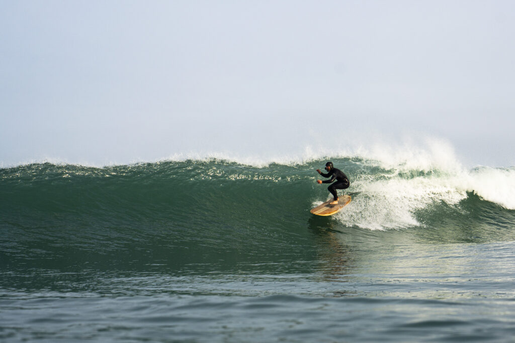 surfing a sustainable, hollow wooden surfboard by Otter Surfboards