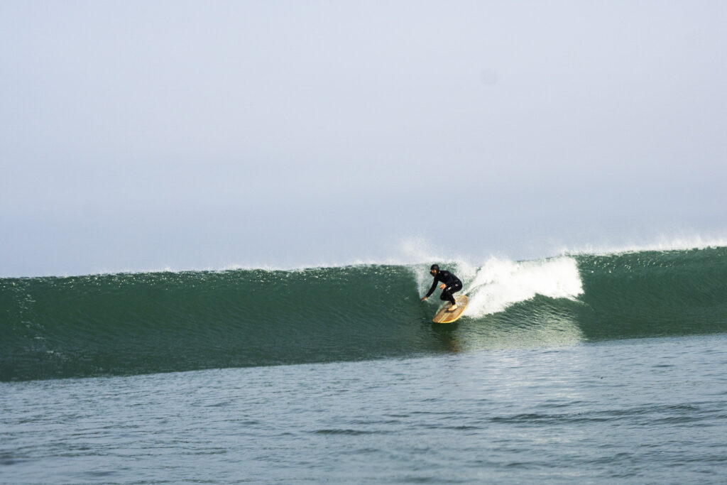 surfing a sustainable, hollow wooden surfboard by Otter Surfboards