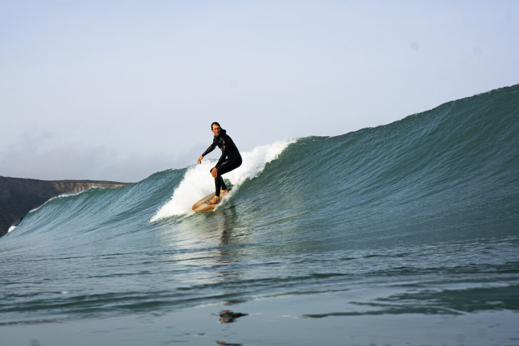 surfing a sustainable, hollow wooden surfboard by Otter Surfboards
