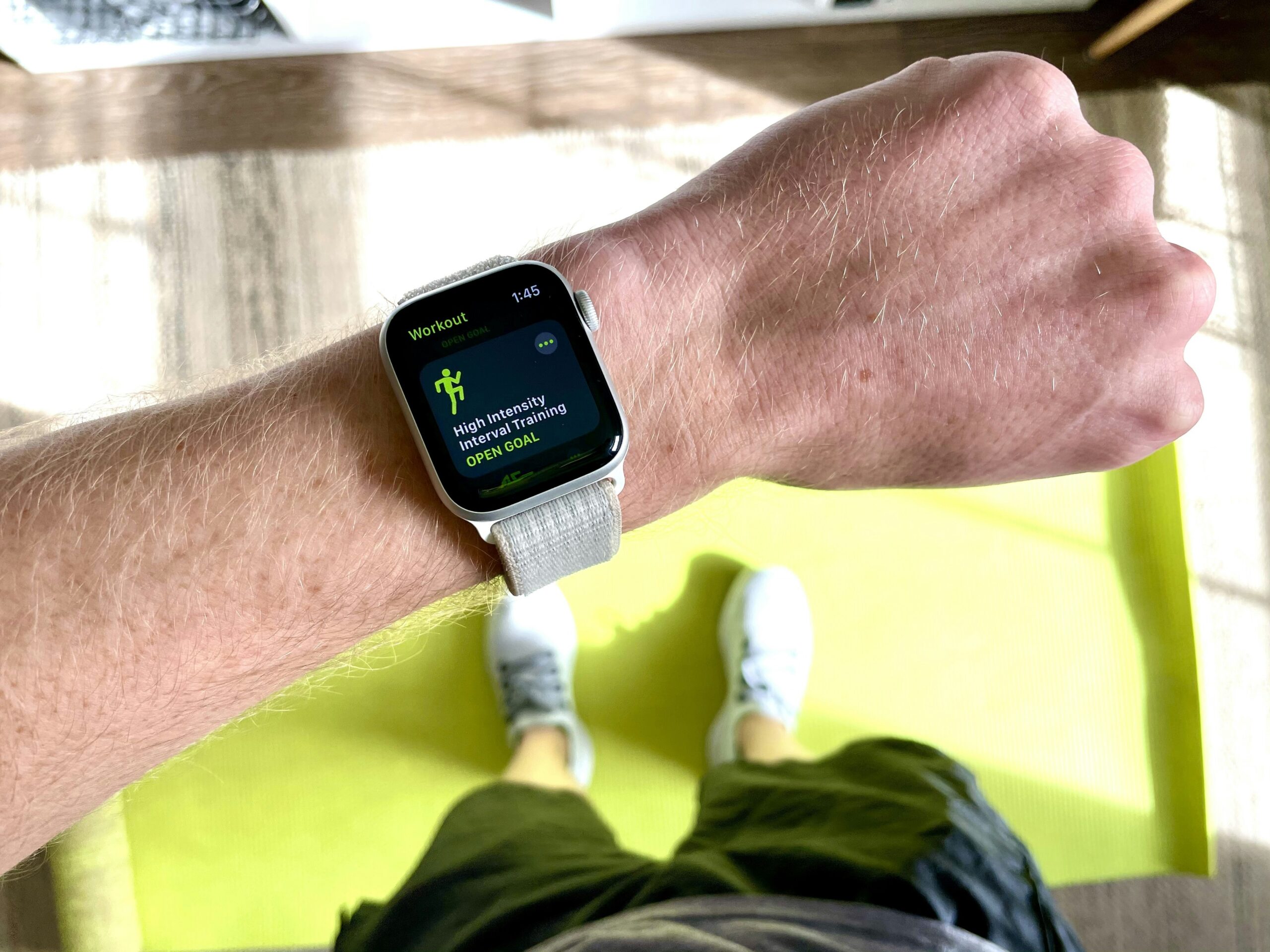 Athlete looks at apple smart watch while standing on a yoga mat