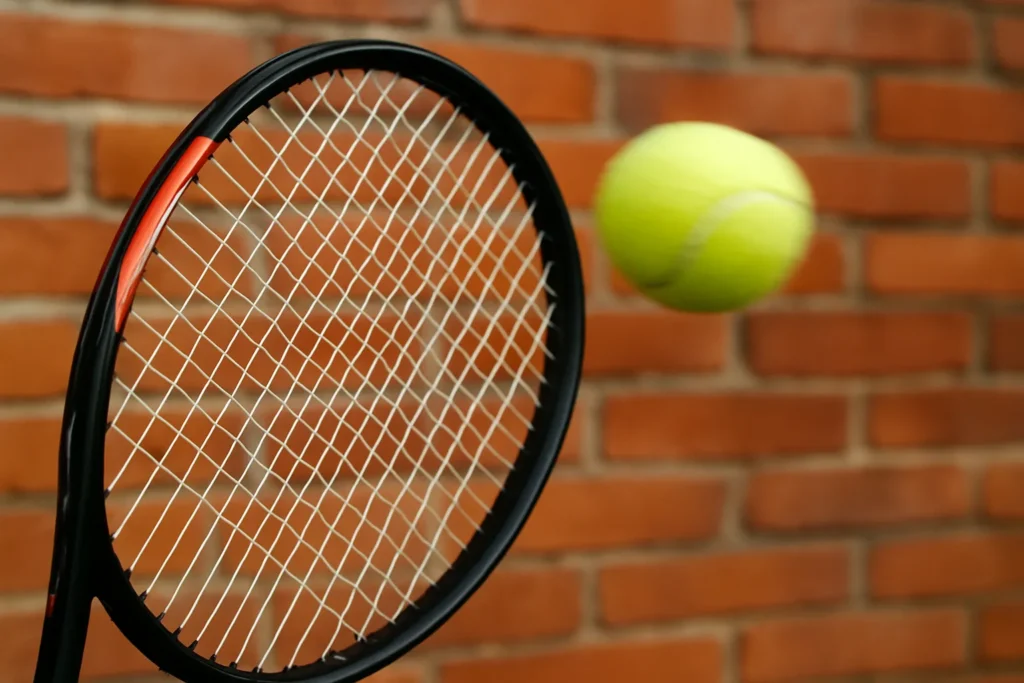 Tennis racket mid-swing with blurred ball returning