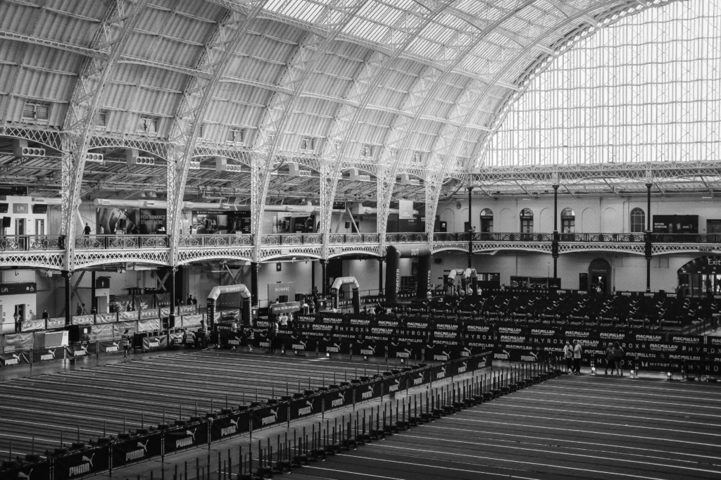 Top-down view of HYROX arena showing athletes on sled push, SkiErg, and run lanes
