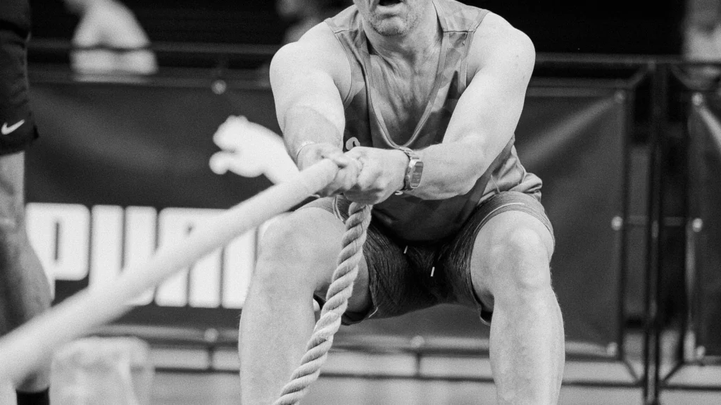 Athlete performing controlled sled pull, rope taut, focus on posture and grip