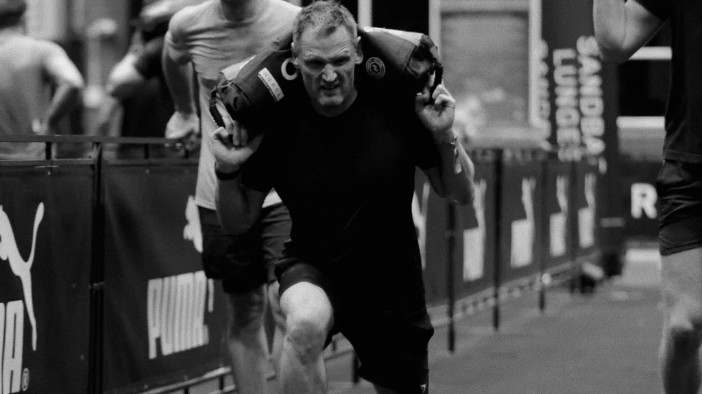 Athlete performing sandbag lunges mid-race