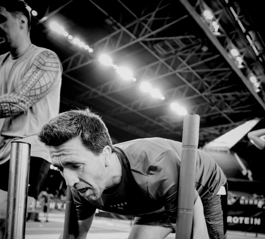 Athlete pushing sled mid-race, visible fatigue and focus