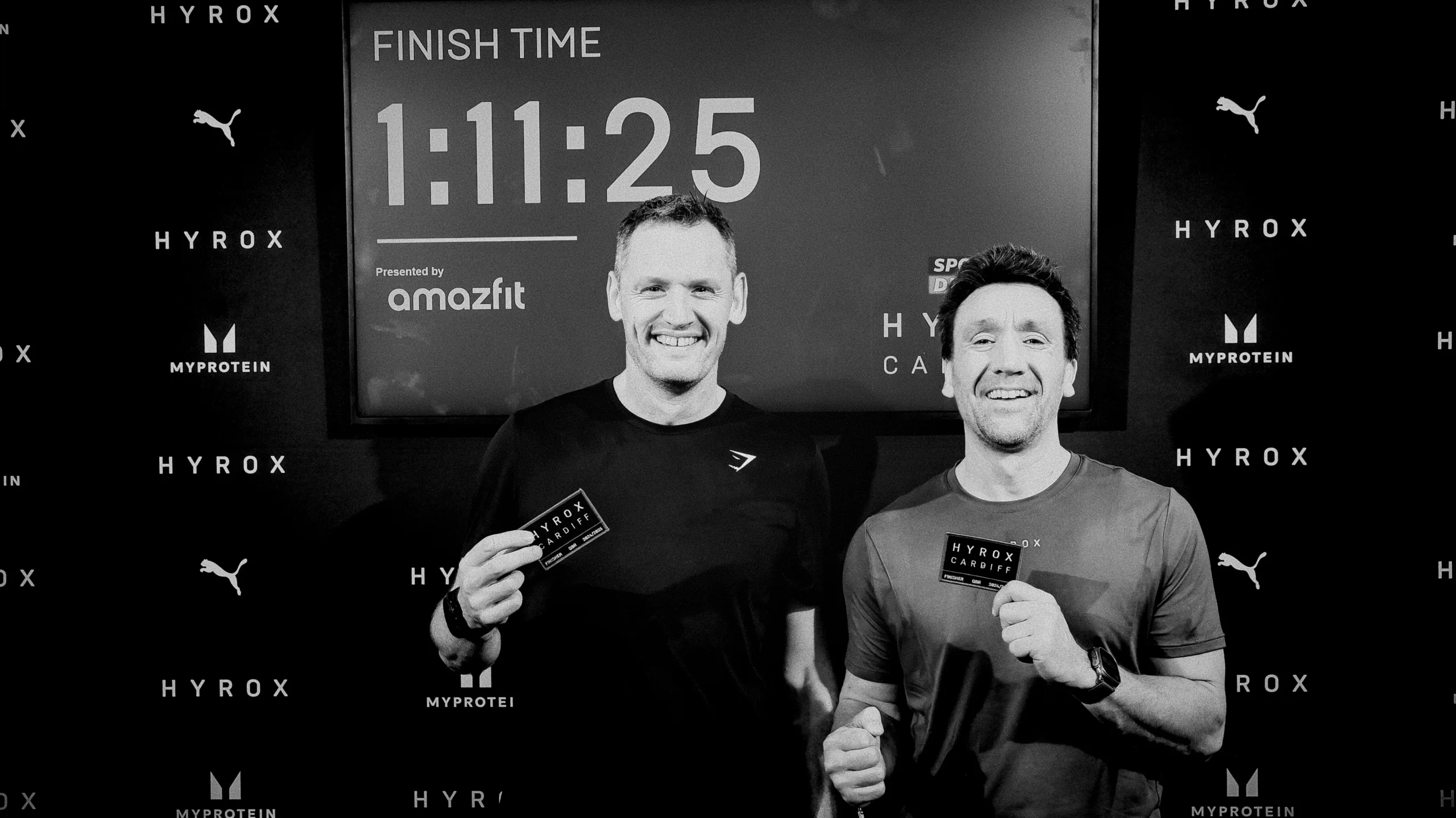 Doubles Team Celebrating finishing HYROX Time in background