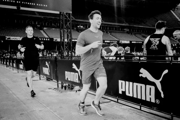 Two HYROX partners tagging between stations in Doubles race, smiling but fatigued