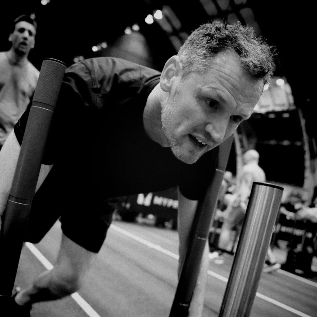 Solo athlete mid-race pushing sled with focus and grit, cinematic light and shadow contrast