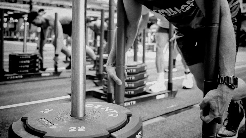 Athlete driving heavy sled across turf lane, low camera angle