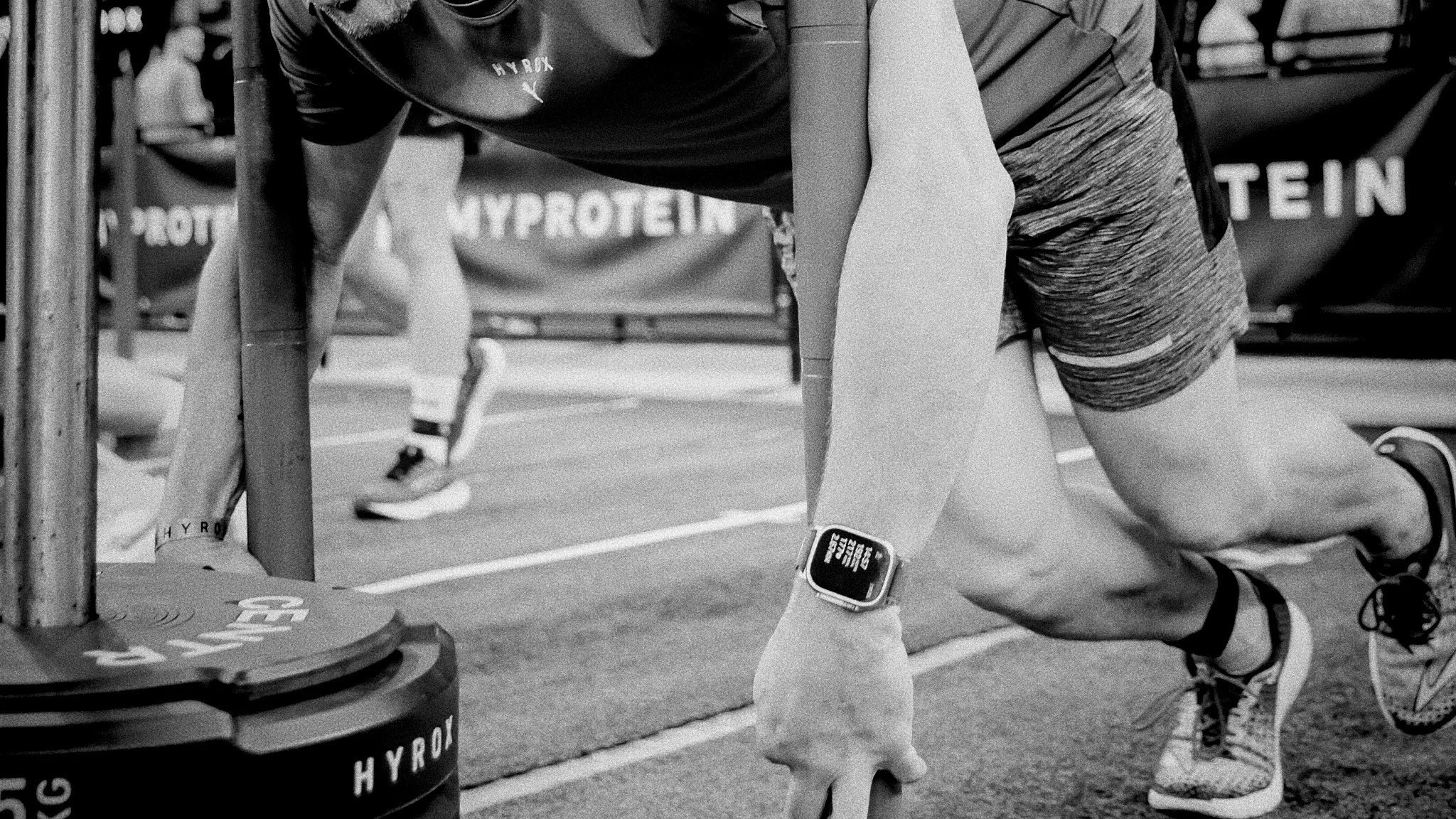 Side angle of athlete driving sled forward, chalk particles in air