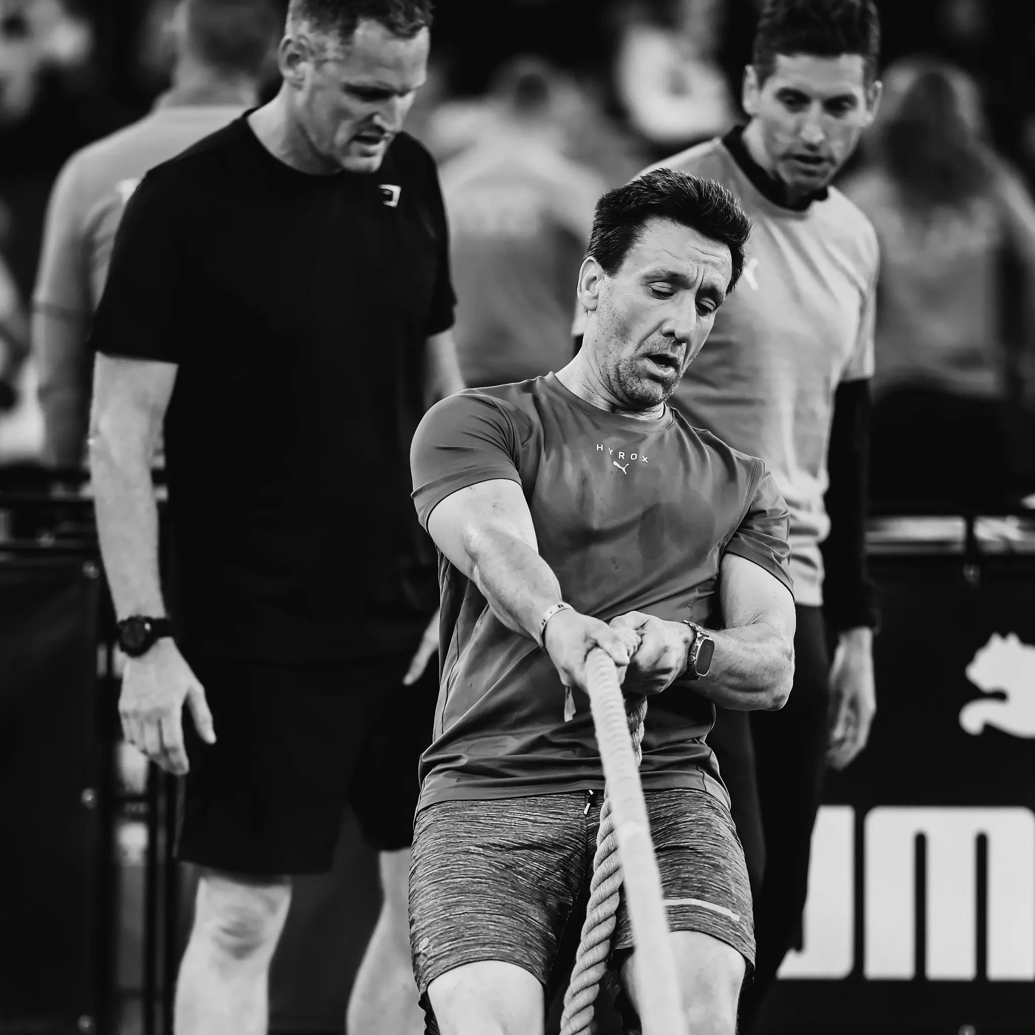Athlete mid-sled pull using thick rope, leaning back with tension through arms and legs