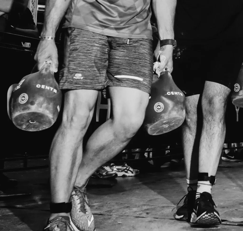 Close-up of athlete’s hands gripping kettlebell handles, veins and chalk visible