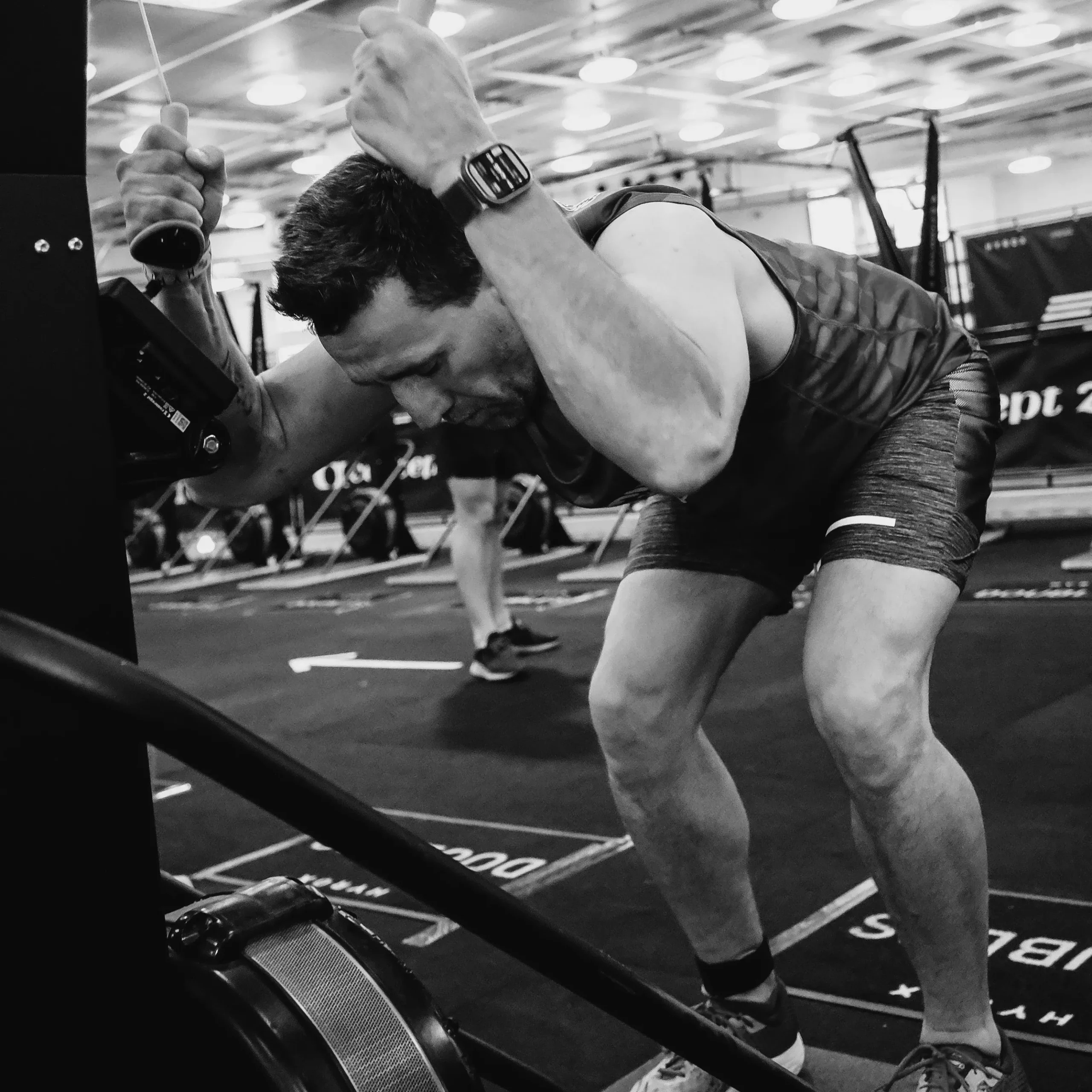 Athlete mid-SkiErg pull, full-body engagement with visible lats and hip drive