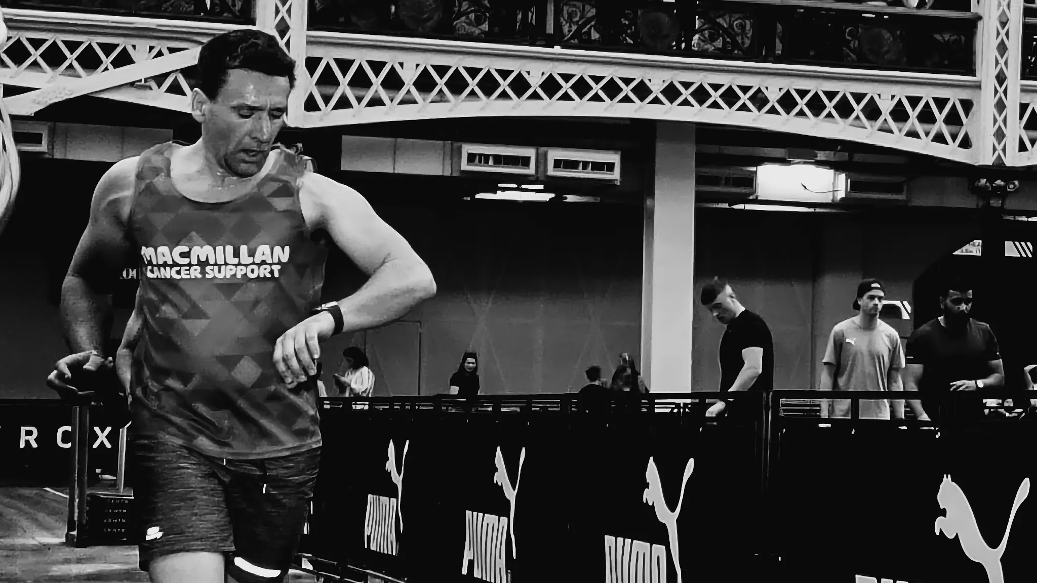 Athlete checking sports watch mid-run inside HYROX venue