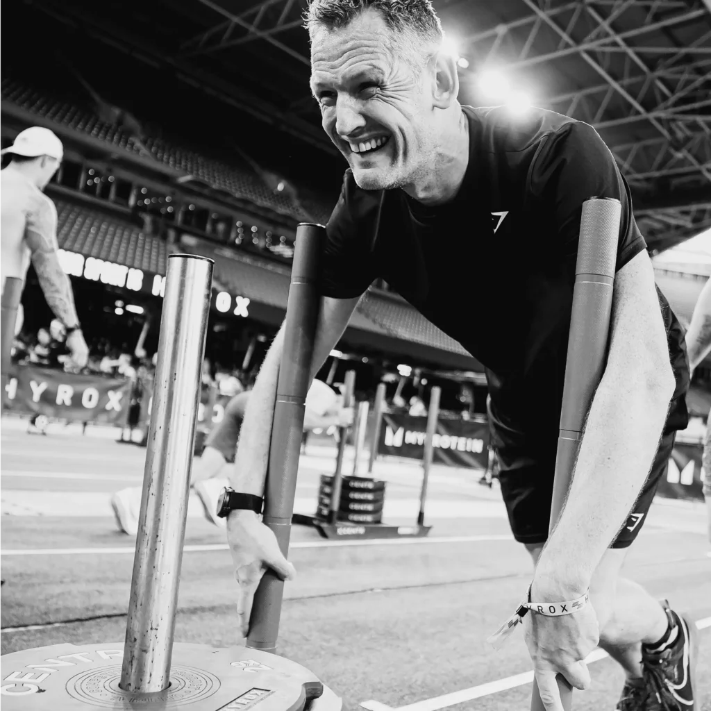 Athlete mid sled push, face clearly working hard but staying composed