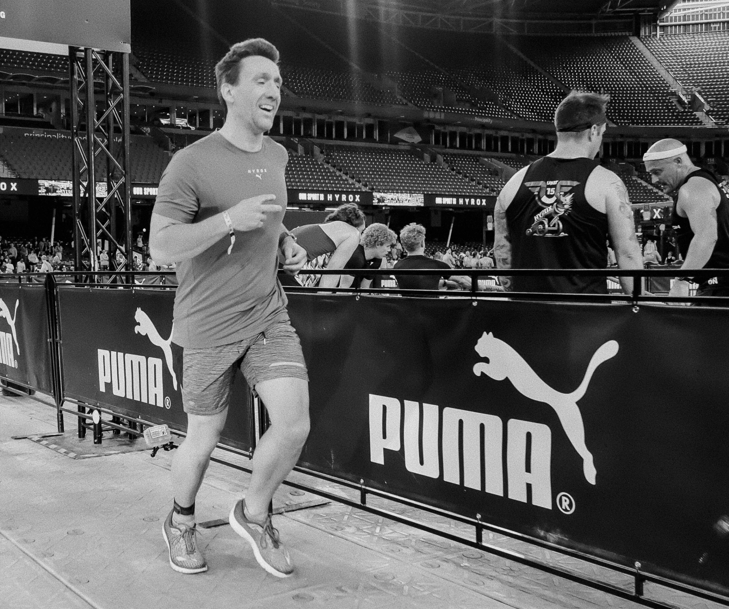 Athlete mid stride, steady breathing, calm posture, arena crowd blurred