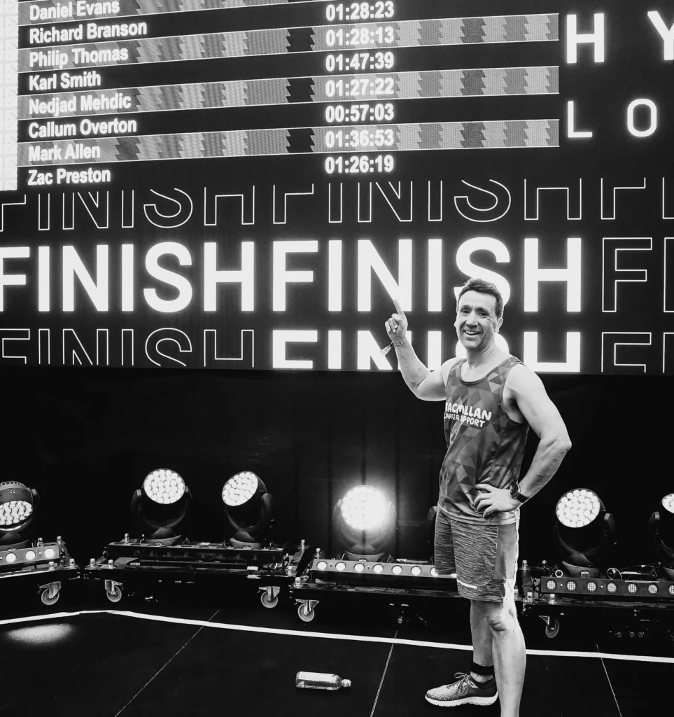 athlete at end of hyrox race pointing at the leaderboard