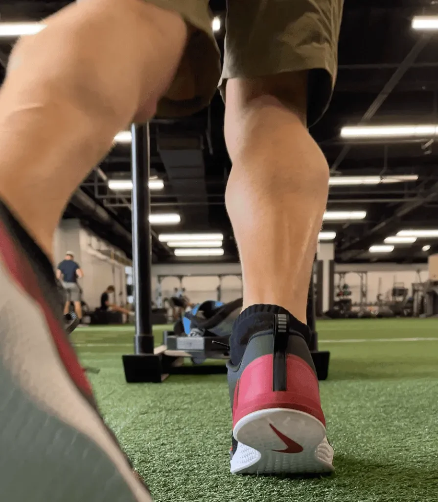 Close up of Nike Metcon shoes on gym floor with sled behind