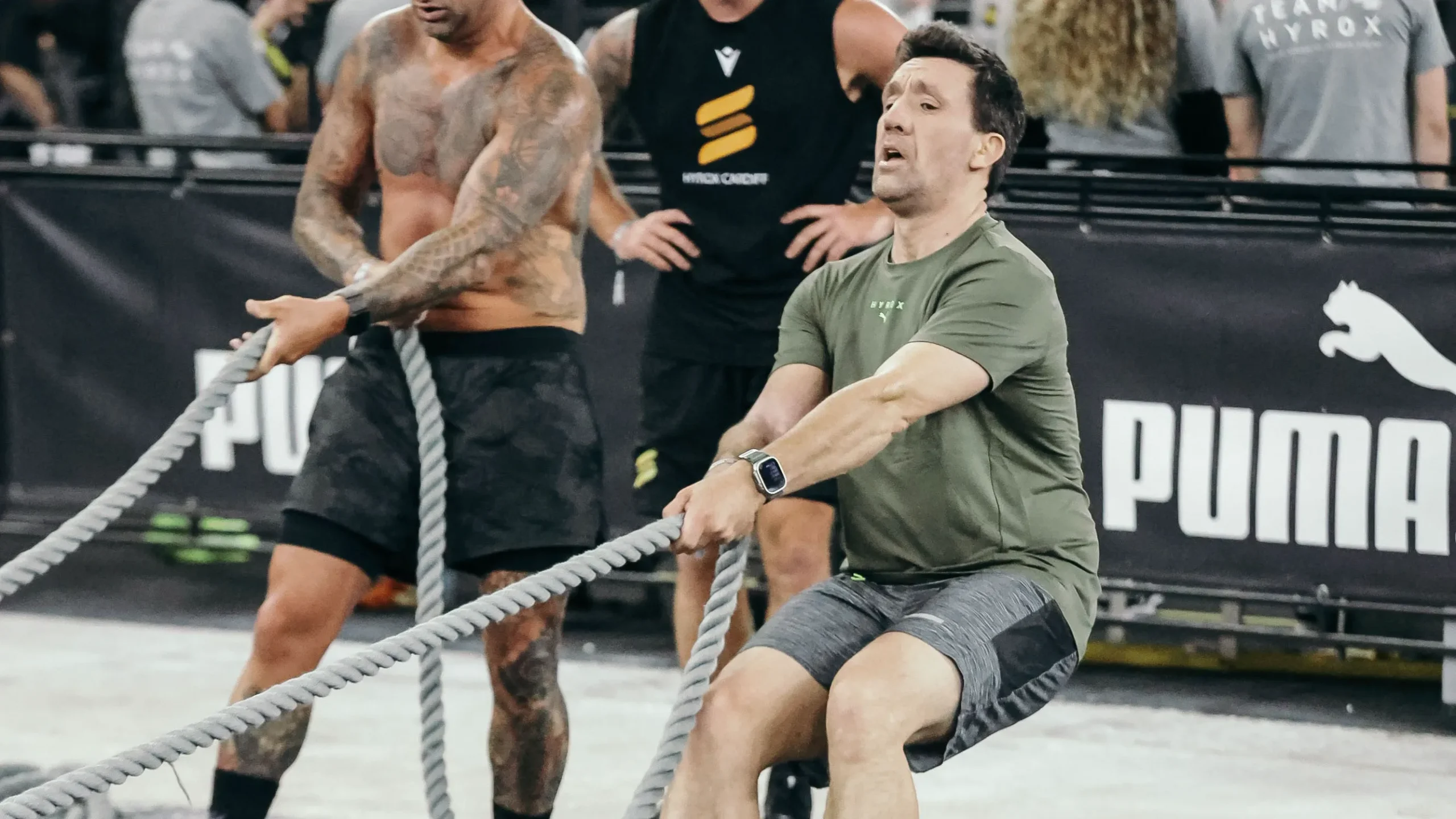 Athlete mid-race wearing performance HYROX apparel, clean sweat detail, moving through sled lane