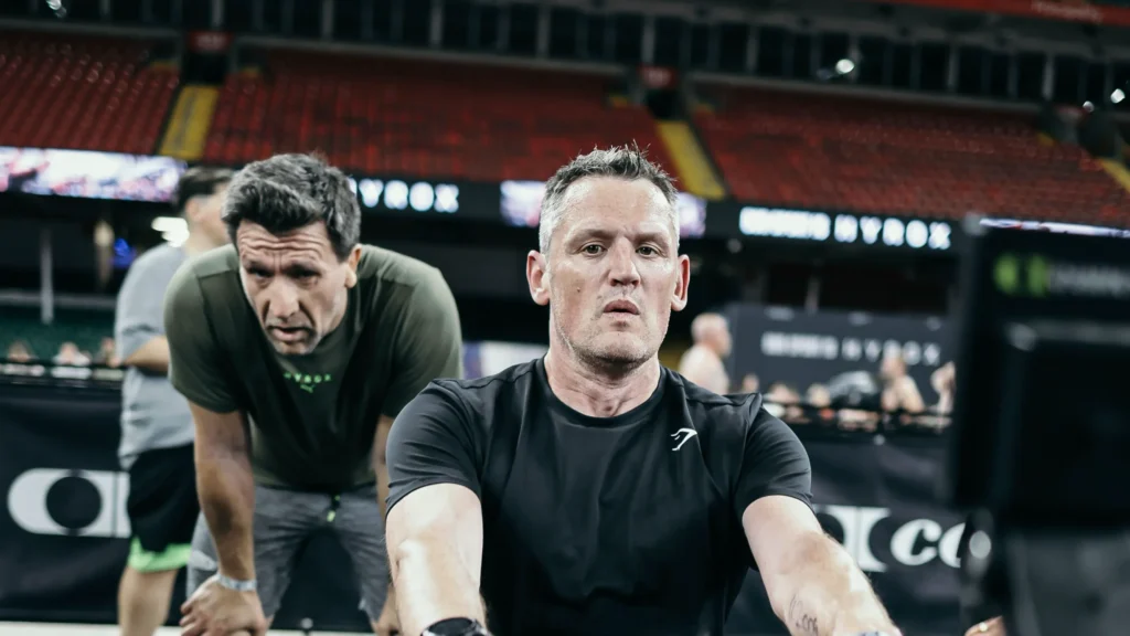 doubles pair mid station wearing performance shorts and technical top, muscles engaged,