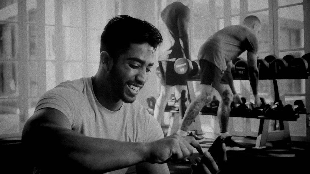 man scrolling on his phone in a gym